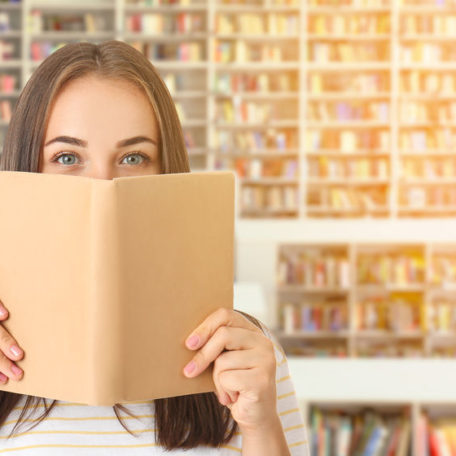 Portrait of beautiful woman with book in modern library